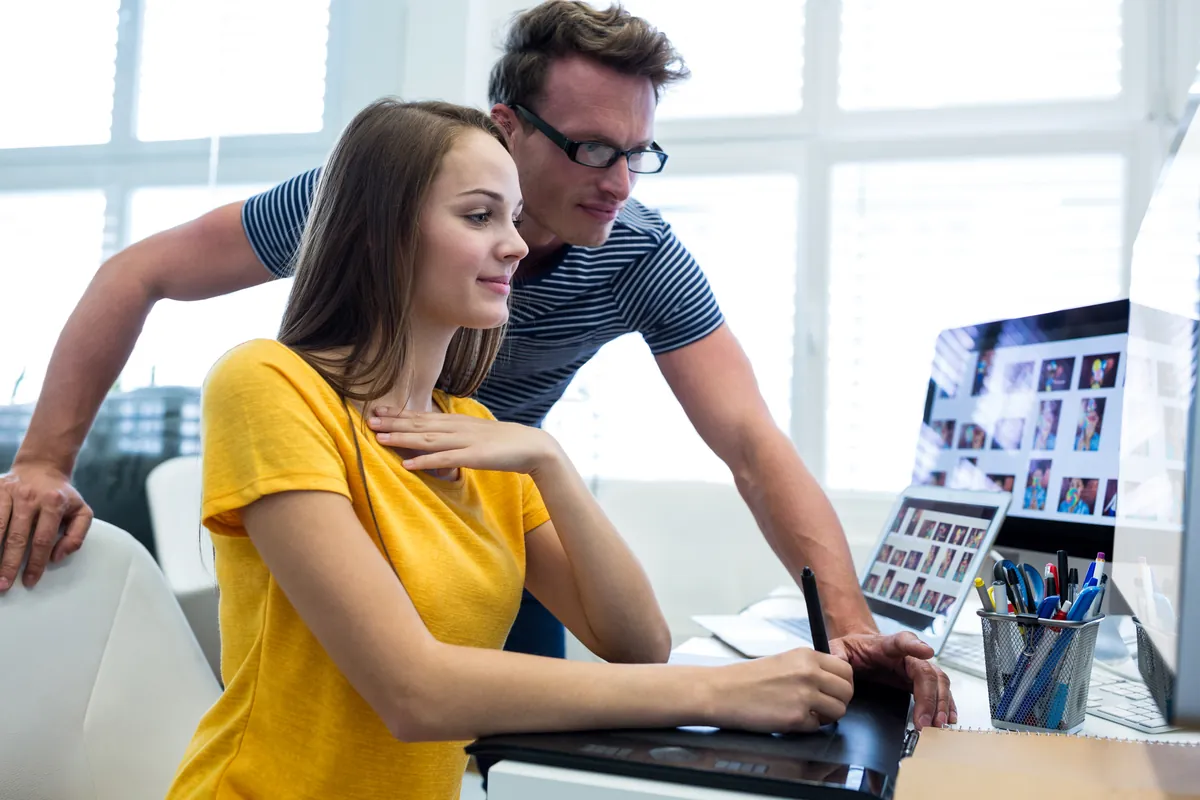 Webdesignerin und Kollege arbeiten mit Grafiktablett an einem Kundenprojekt – Agentur-Alltag