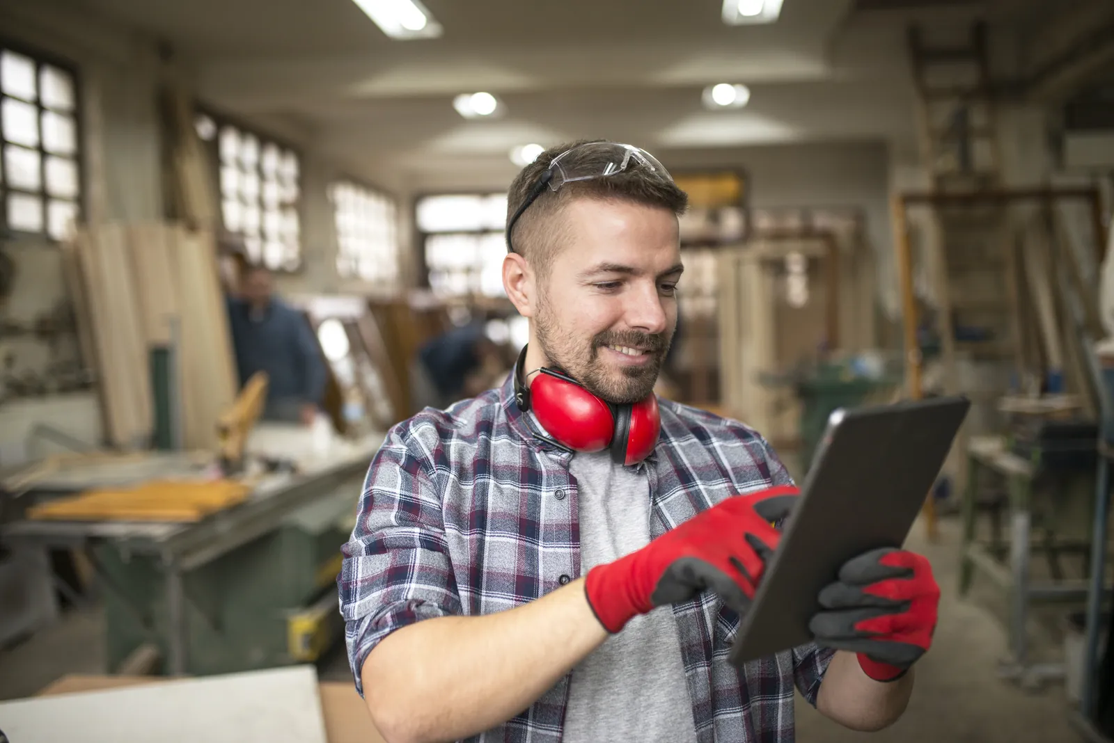 Tischler prüft ein Angebot auf dem Tablet in der Werkstatt – Neukunden gewinnen im Handwerk