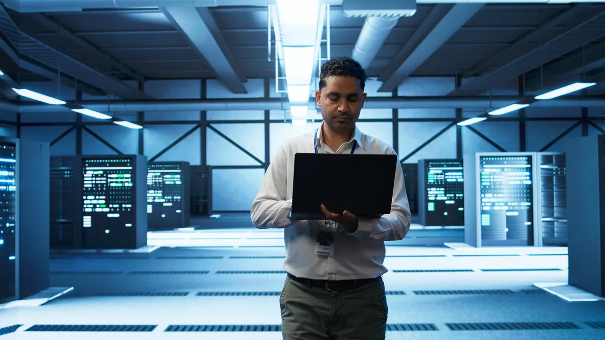 IT-Administrator mit Laptop im Serverraum – Betreuung von Hosting- und IT-Kunden
