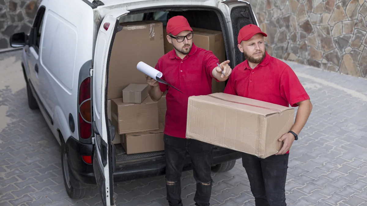 Zwei Umzugshelfer laden Kartons aus dem Transporter und prüfen die Liste – Umzug & Entrümpelung